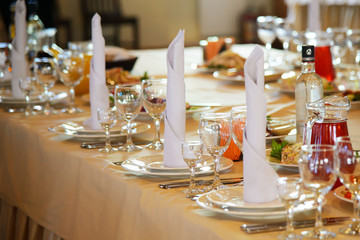 Festive table in the restaurant. Served with dishes and Cutlery table. A table with a tablecloth, napkins and plates for food. A festive Banquet. Holiday and celebration in the room.