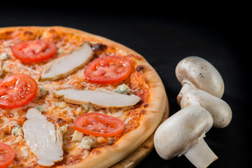 closeup Tasty pizza with tomatoes, cheese, basil and ham on a bl