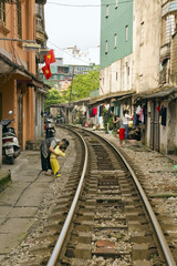 Fototapeta na wymiar train passing through streets of hanoi slums, vietnam
