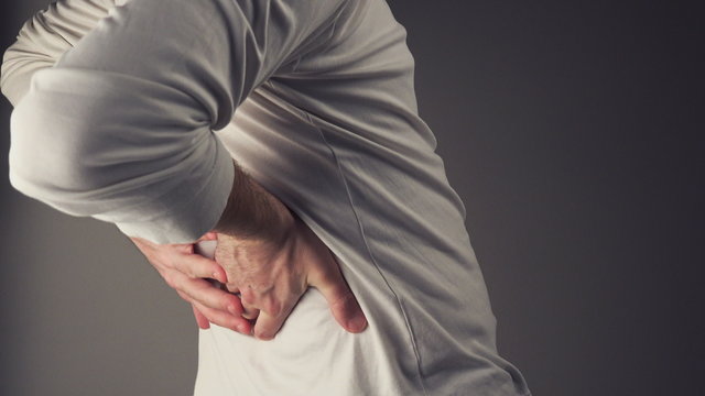 Severe back pain, man suffering from back ache having painful cramps.