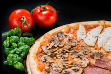 closeup Tasty pizza with mushrooms, ham and pickles on a black b