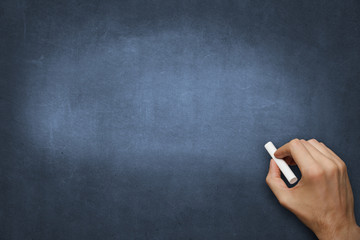 hand with chalk on empty blackboard - copyspace background