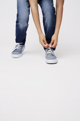 Young kid tying sneaker lace in studio, low section
