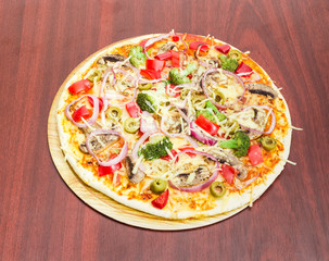 Vegetarian pizza with vegetables, mushrooms and olives on wooden