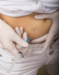 Closeup of a slim girl's hands as she gives herself a shot. She holding a syringe