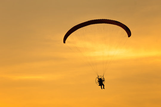 Paramotor flying in the sunset sky, Silhouette shot.