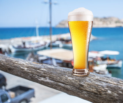 Glass of light beer on the  seaside bar counter.Boats in the doc