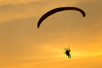Paramotor flying in the sunset sky, Silhouette shot.
