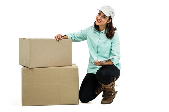 Delivery woman with clipboard kneeling by box - Powered by Adobe