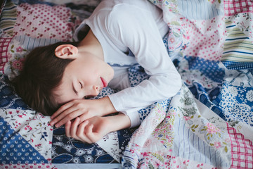 teenager sleeping on the bed covered with a blanket