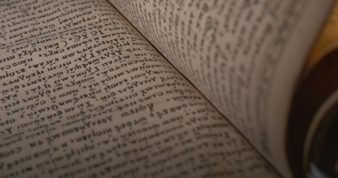 Man in White Gloves is Leafing Through The Old Book, Script, Letters Closeup, Bookmarks among Pages Closeup, Ray of Light upon the Book, Darkness
