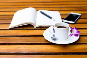 Cup of coffee with flower and note book  on the table
