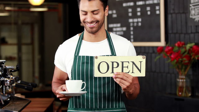 Smiling waiter holding sign and coffees cup