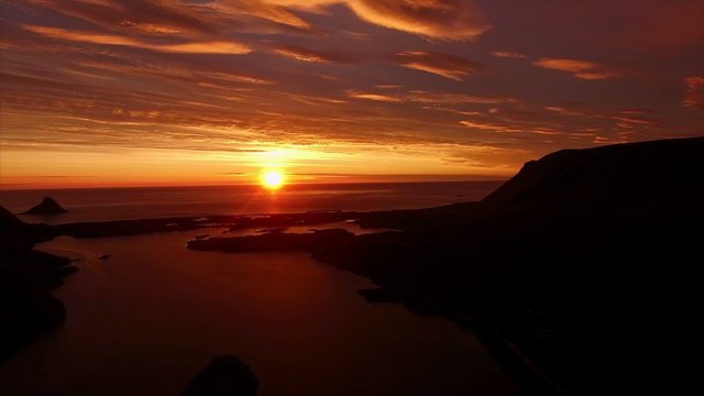 Midnight sun casting red light over the ocean on island of Andoya in Norway. Aerial 4k Ultra HD.