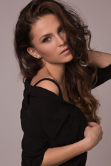 Naklejka premium Woman with beauty long curly brown hair posing at studio