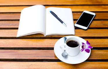 Cup of coffee with flower and note book  on the table