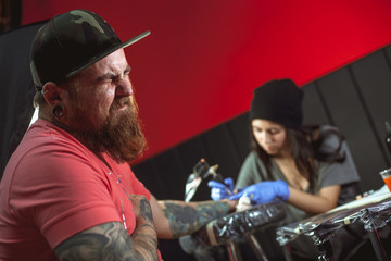 Beautiful brunette girl makes tattoo. Tattooist makes a tattoo. Closeup