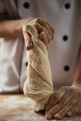 Close-up of female chef hands kneading the dough on the board. Bread preparation. 