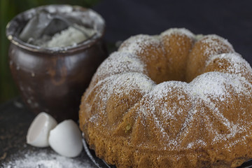 Rührkuchen mit Puderzucker und Backutensilien