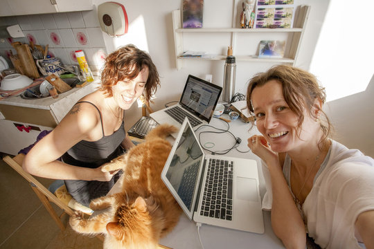 two women working online in the kitchen and taking selfie