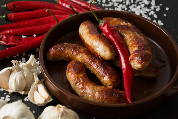 Several sausages in the pan with garlic and red pappers