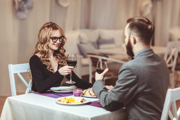 Beautiful young couple with glasses of red wine in luxury restaurant