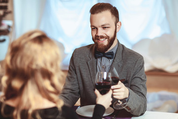 Beautiful young couple with glasses of red wine in luxury restaurant