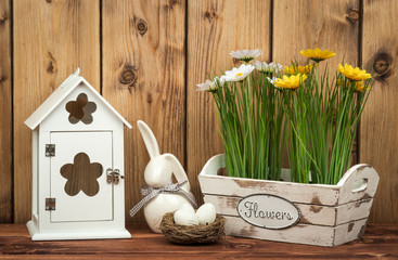 Easter decorations - wooden box with flowers and eggs on the wooden background.