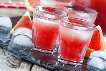 Cool juice from blood orange with ice cubes on a dark background