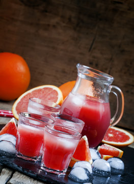 Cool juice from blood orange with ice cubes on a dark background