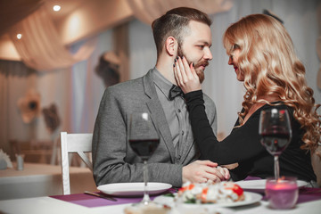 Beautiful young couple with glasses of red wine in luxury restaurant