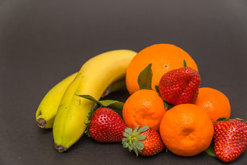  banana, orange,strawberries and Three tangerine with leaves on a beautiful gray background, beautiful colors and composition