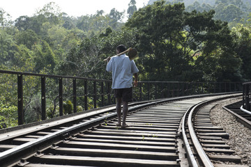 Hombre de espalda caminando en el medio de una ferrovía