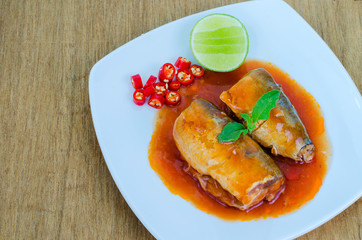 Canned fish spicy salad in white disk on wooden