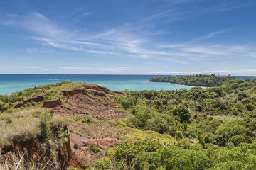Fototapeta na wymiar Red rocks on green jungles and turquoise water on a colorful landscape in Madagascar, Africa.