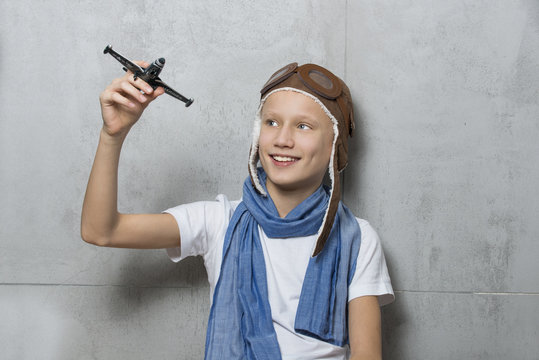 Mały marzyciel w czapce pilotce bawiący się samolotem