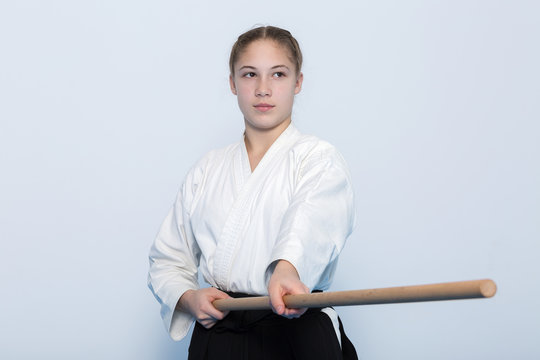 A girl in black hakama standing in fighting pose with wooden jo stick