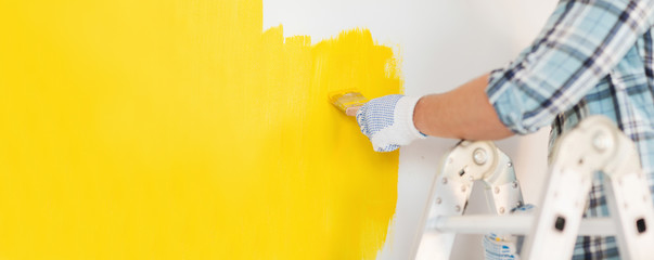 close up of male in gloves painting a wall