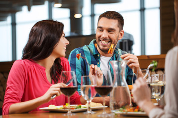 happy couple with friends eating at restaurant