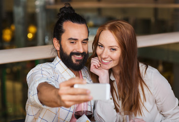 couple taking selfie by smartphone at restaurant