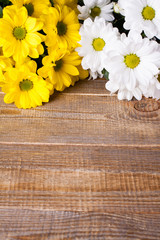 White and yellow oxeye daisy flowers bouquet on wooden background.