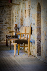 Old chairs in balcony with wooden floor and stone made walls. Orthodox monastery