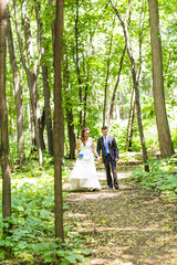 Newly married couple walk on park paths holding hands 