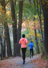 Athlete runners feet running on the autumn forest road