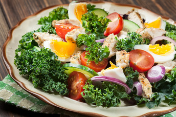 Fresh salad with chicken, tomatoes, eggs and lettuce on plate