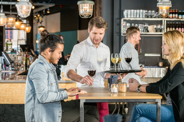 Waiter Serving Wine To Customers In Bar