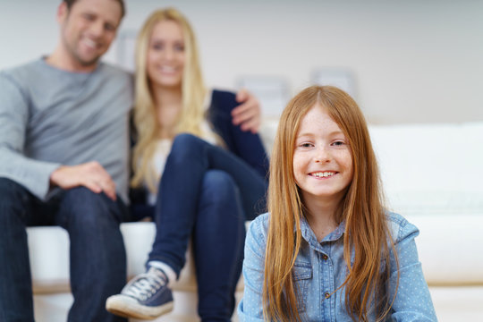 gl&uuml;ckliches kleines m&auml;dchen mit seinen eltern im hintergrund