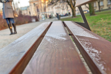 Fototapeta na wymiar Little snow on city wooden bench in Warsaw