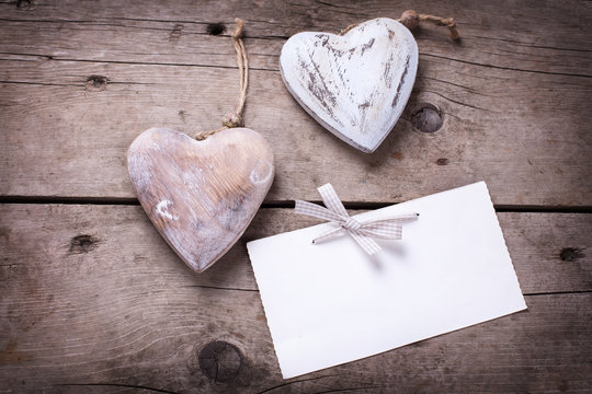 Two decorative  hearts  and empty tag on aged wooden background.