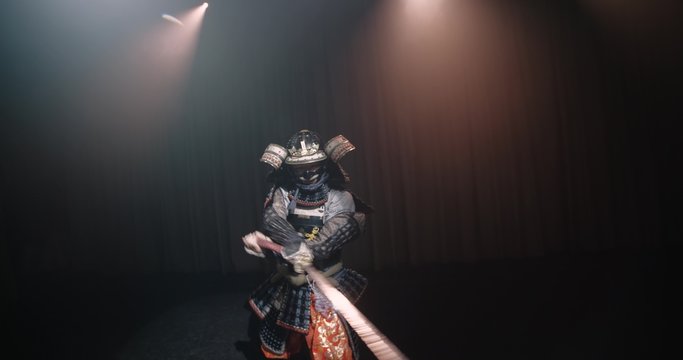 Japanese samurai in the historical suit threatens with a sword , posing for the camera, slow motion